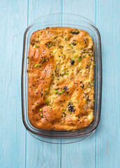 Homemade cheese and scallions pie in a cooking tray on blue wooden table