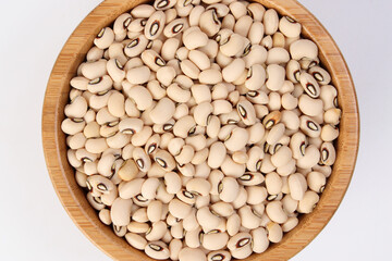 Blackeye beans in wooden bowl top view on white background