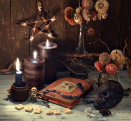 Vintage still life with old diary book, burning candles, dry flowers and runes.