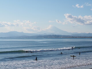 Obraz premium 富士山の見える雄大な景色の前で波を待っているサーファー