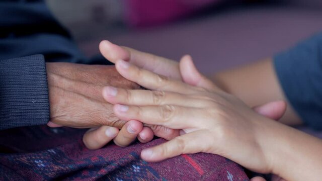 Hands of a young woman softly touching to hands of the old woman for consolation and encourage, for family and difference age, selective focus shallow depth of field
