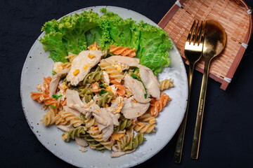 Macaroni stir fried with chicken in ceramic plate on black background