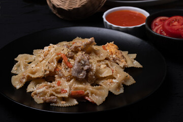 Macaroni in a black ceramic plate on a black table