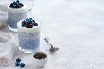 Fototapeta na wymiar Two transparent glasses of healthy chia pudding wih blue butterfly pea tea and berries