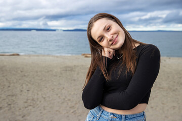 Teenage girl outside at Alki Beach in West Seattle with a view of the Puget Sound and the city of Seattle in Washington State. 