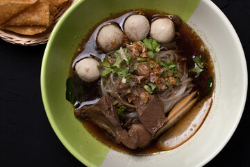 Braised pork noodles in a cup on a black background