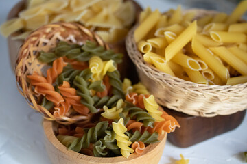 Dried macaroni in wooden cup on white background