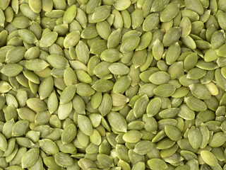 Organic raw peeled pumpkin seeds as background, top view.  Vegetarian snack or Healthy food concept.