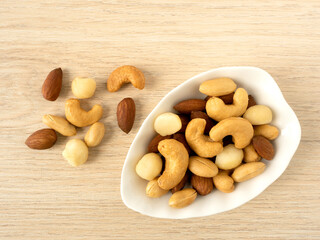 Organic cashew nuts, almond nuts and macadamia nuts and peanut  in ceramic bowl on wooden table. Mix nut healthy ingredients food.