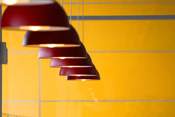 Red hanging lamps in front of yellow wall