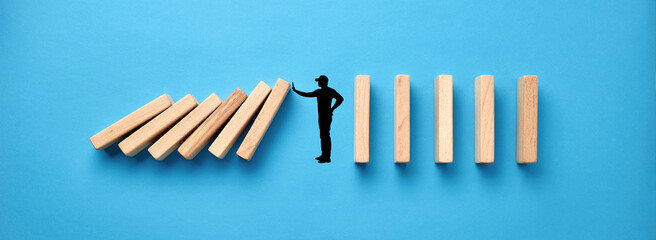 Hand drawing silhouette of a man making a stop gesture to prevent wooden dominos from collapsing