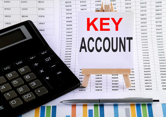 h KEY ACCOUNT on small easel with charts, pen and calculator.Business concept.