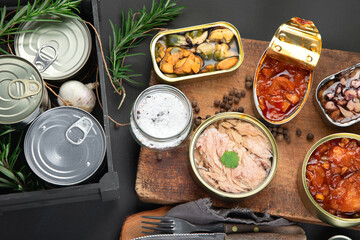 Various canned fish and seafood in aluminum cans. On dark gray background.