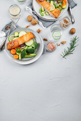 Two portions of homemade fresh salmon with vegetables on a light background.