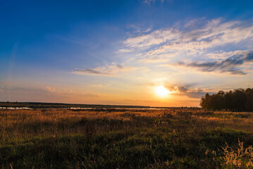 summer landscape with meadow and beautiful sunset with forest and river