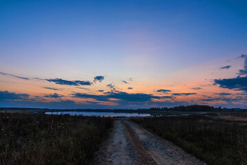 landscape with lake and road at sunset in autumn evening