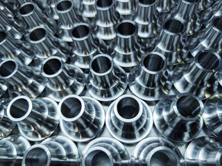 a batch of shiny steel cnc aerospace parts production - close-up with selective focus for...