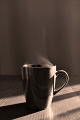 Tea or coffee cup on wood table. Black and white photo. Vintage style photo. Copy space is above the cup. Sepia photography.