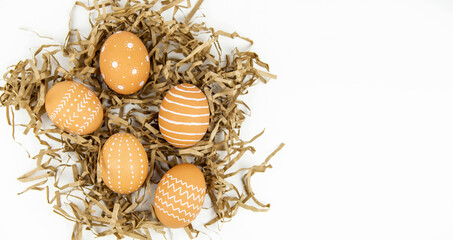 Eggs of natural color with a minimal white pattern on paper craft grass on a white background.