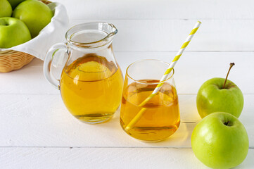 Fresh homemade apple juice and green apples on white table. Healthy morning beverage.