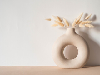 Round stylish ceramic vase with dried flower lagurus - obrazy, fototapety, plakaty