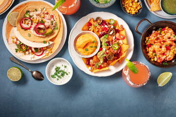 Mexican food, a flat lay. Nachos, tacos, and other dishes, shot from the top on a blue background with a place for text