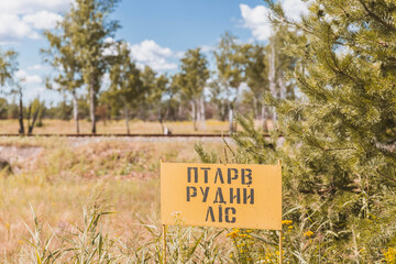 Chernobyl, Ukraine, August 2020: «Red Forest» warning sign. The forest changed its color due to...