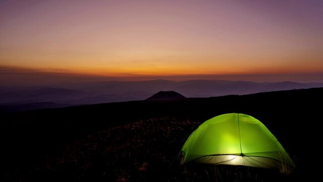 timelapse of Sicily sunset on volcanic landscape, wild camp with illuminated tent in Etna park