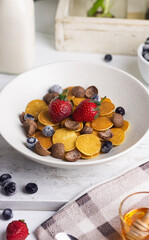 Cereal Pancakes or mini pancakes for breakfast, served with blueberries, strawberries and honey. Bright mood photography concept. White background. 