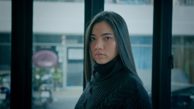 Beautiful brunette woman with lovely long hair in a black sweater looks straight at the camera in slow motion, handheld shot on bmpcc 6k