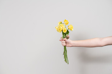 the man's hand holds out a bouquet of wilted flowers and shows a fig. separation concept. layout...