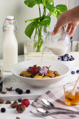 Cereal Pancakes or mini pancakes for breakfast, served with blueberries, strawberries and honey. Bright mood photography concept. White background. 