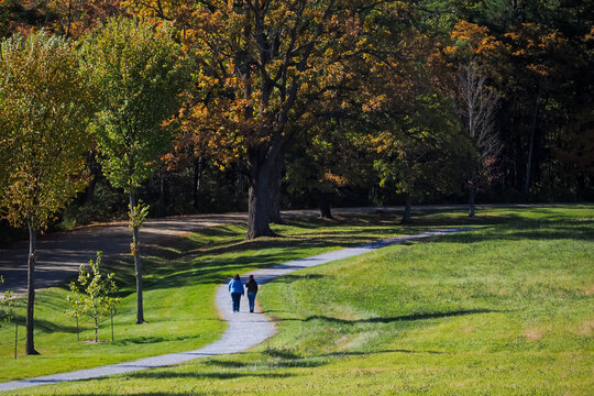 People Walking Along Path On A Sunny Morning In October Under Autumn Light. Burlington, Vermont