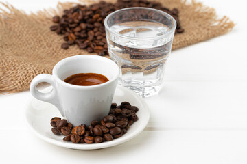 Cup of espresso with glass of water on white table