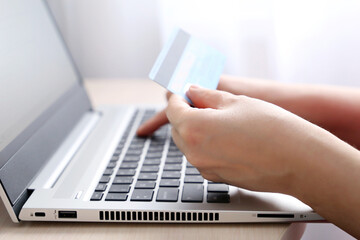 Woman holding credit card types on laptop keyboard. Concept of online shopping and payment,...
