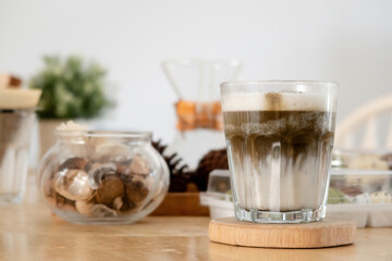 Japanese hojicha green tea drink is a latte in a glass placed on a wooden tray.