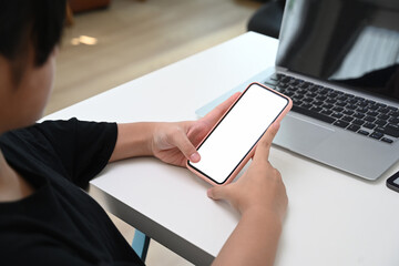 Schoolgirl studying online lesson with laptop computer and searching information on smart phone at home. Online education concept.