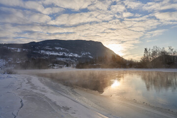 The river is about to freeze. It is very cold and the river is much warmer than the air, therefore the smoke or the damp from the river. Shot at Gol, Norway in February. Minus 20 degreases Celsius. 