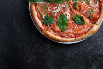 Tasty appetizing vegetarian pizza on dark stone background, top view 