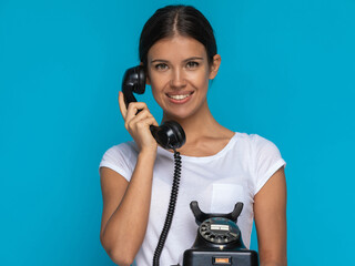 casual woman talking on an old telephone and smiling