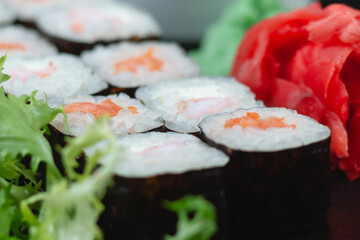 Sushi rolls with salmon, rice, eel and soy sauce on dark stone background