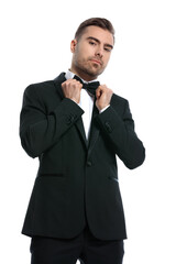 elegant young businessman in black tuxedo fixing bowtie