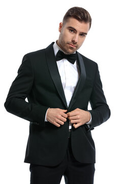 portrait of cool fashion man buttoning black tuxedo
