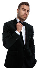 confident elegant guy in black tuxedo adjusting bowtie