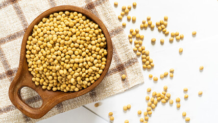 Organic soybeans in wooden container on white table, top view