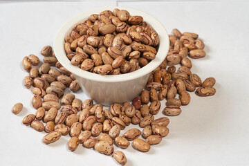 Closeup of organic borlotti beans in porcelain bowl on white background, healthy eating