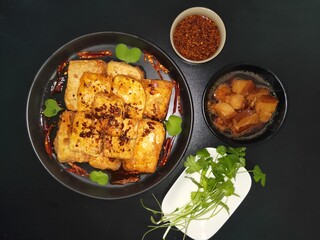 Fried tofu, braised pork and coriander on black background, top view, homemade traditional Chinese cuisine