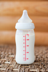 Bottle with breast milk for baby on wooden background. Maternity and baby care concept. Top view. - 411727953