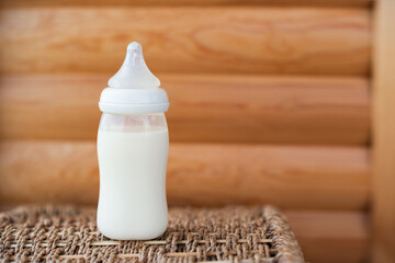 Bottle with breast milk for baby on wooden background. Maternity and baby care concept. Top view. Free copy space. - 411727999