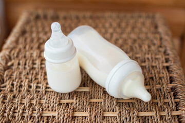 Bottles with breast milk for baby on straw basket background. Maternity and baby care concept. Top view. - 411728178